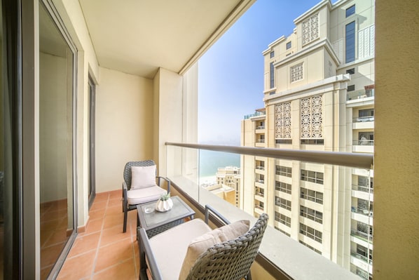 A balcony with a table, chairs, and a view of high-rise buildings.