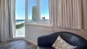 Una habitación con vista a la playa y un edificio alto.
