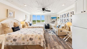 Un dormitorio con dos camas, ventilador de techo, vista a la playa y un letrero que dice 'Beach House'.