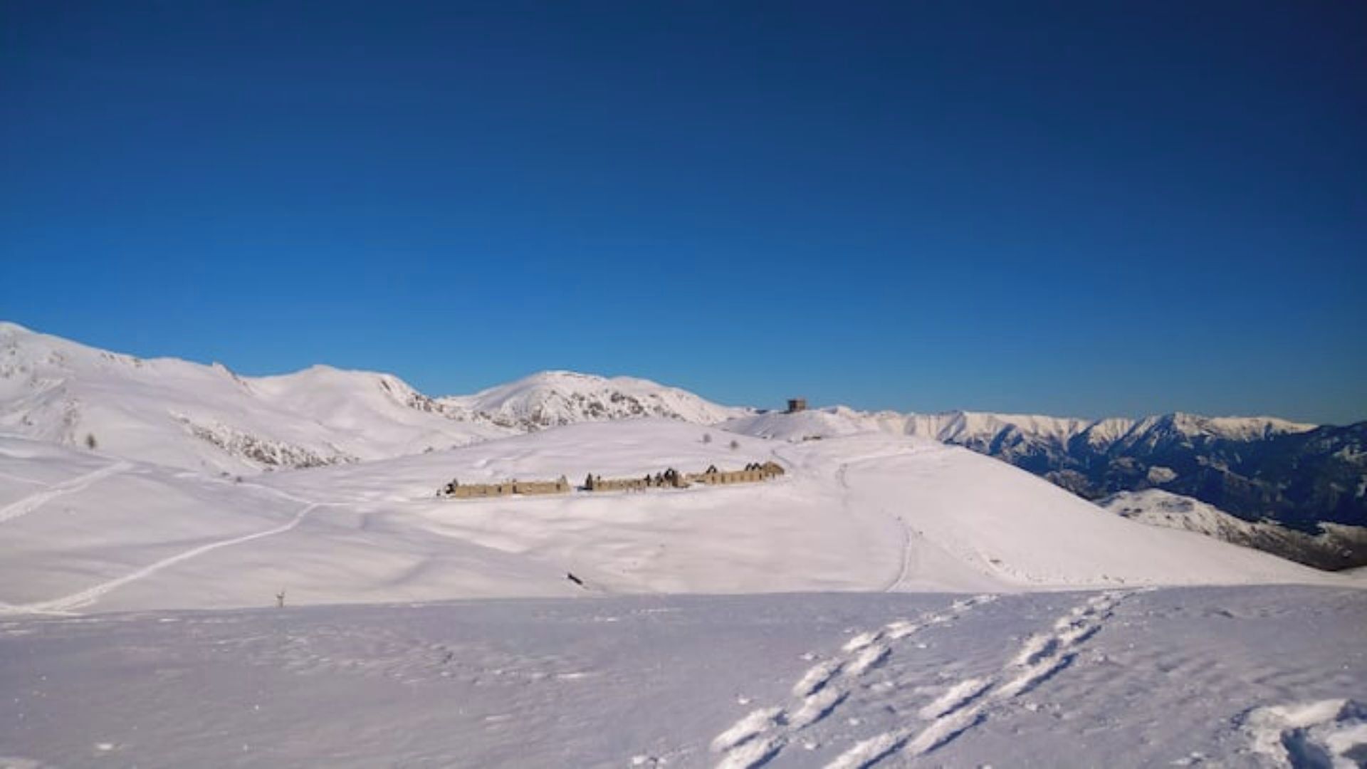 A snow-covered mountain landscape with a clear blue sky.