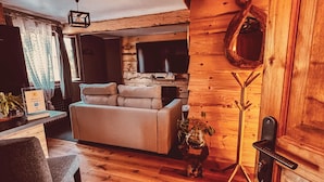 Ein gemütliches Blockhaus-Interieur mit einer Couch, einem Esstisch und einem Fernseher.