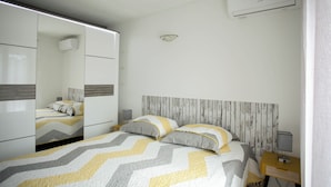 Une chambre à coucher moderne avec une armoire à miroir, une tête de lit en bois et une table de chevet avec une lampe.