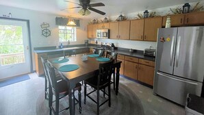 A kitchen with a central island, wooden cabinets, a stainless steel refrigerator, and a ceiling fan. - Captain's Quarters -Water Front- Water Access-Pet Friendly-NO LINENS (Chincoteague)