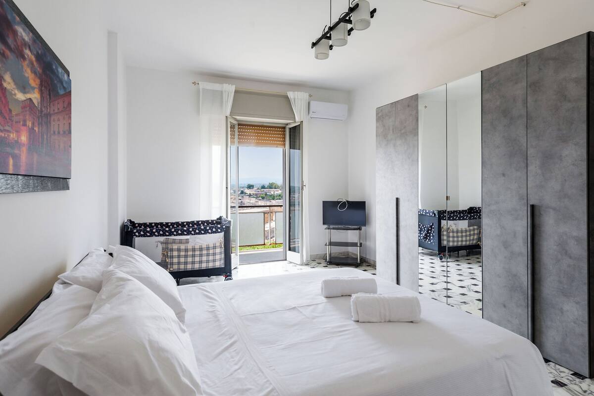 A hotel room with a large bed, a TV, a balcony with a view, and a wardrobe.