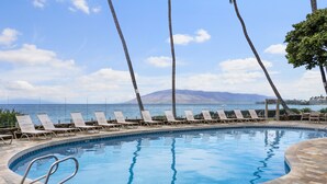 A swimming pool with lounge chairs and a view of the ocean. - Royal Mauian #219 2 Bedroom Condo by RedAwning (Kihei)