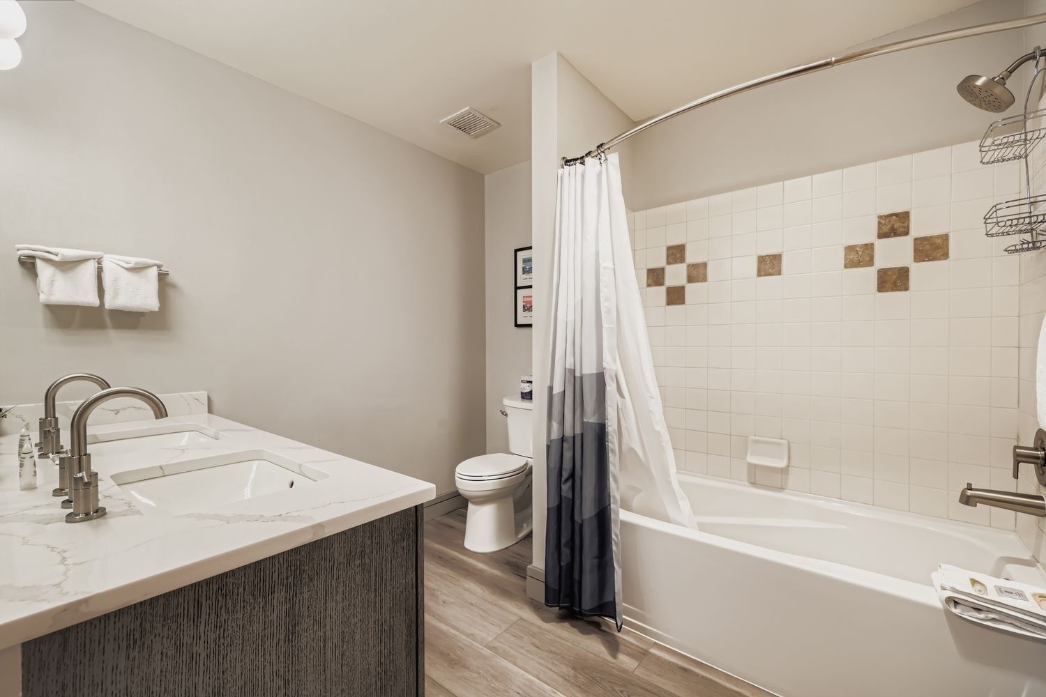 Ein modernes Badezimmer mit einem мраморный Waschbecken, einer Toilette und einer Badewanne mit Duschkopf.