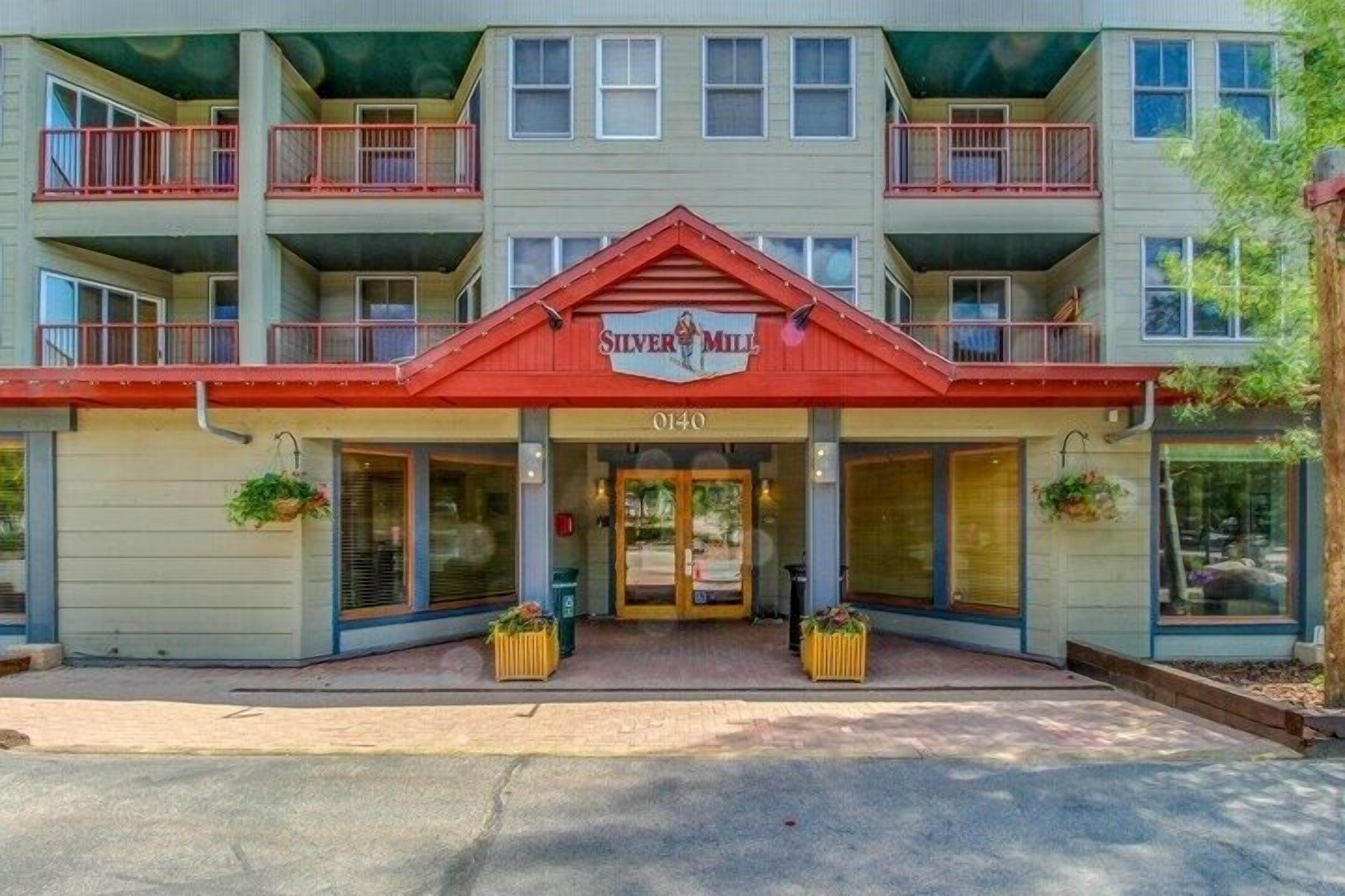 A multi-story hotel with a red and beige facade, balconies, and a sign reading "Silver Mill".