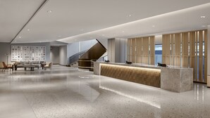 A spacious lobby with a reception desk, seating area, and a staircase.