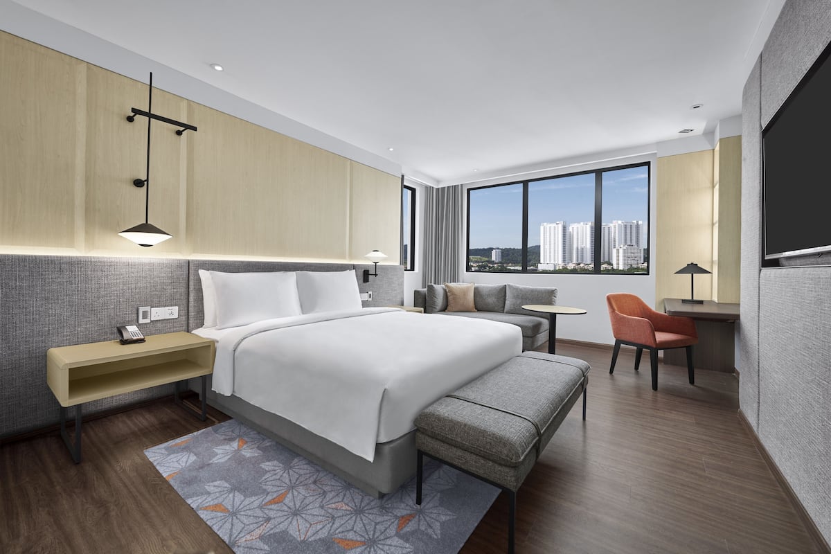 Una habitación de hotel moderna con una cama grande, un escritorio y vistas a la ciudad.