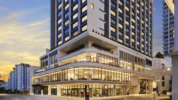 A multi-story hotel with a modern design, featuring a prominent entrance and a landscaped area in front.