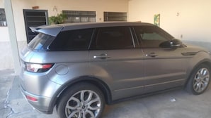 Un SUV plateado estacionado en un garaje con piso de concreto y pared blanca.