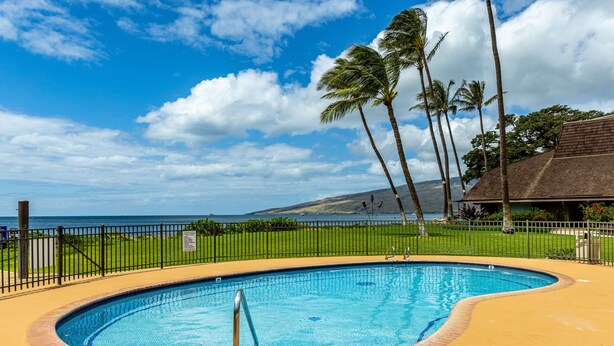 A swimming pool with a view of the ocean and palm trees. - Maalaea Surf #g-2 1 Bedroom Condo by RedAwning (Kihei)
