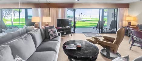 A modern living room with a sofa, armchairs, a coffee table, and a TV.