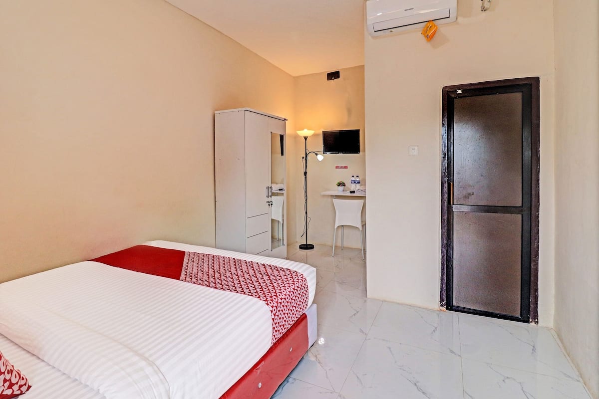 A hotel room with a bed, a desk, a wardrobe, and a door.