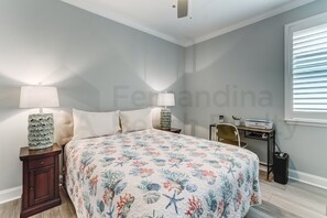 Cozy retreat with a large bed, nightstand, desk, and comfortable chair.