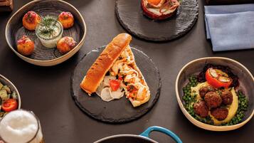 Une variété de plats sont disposés sur la table, notamment un filet de poisson accompagné de pommes de terre, un petit pain et plusieurs petites assiettes contenant différents amuse-gueules.