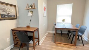 Un comedor con una mesa y sillas de madera, una lámpara y un ventanal con persianas.