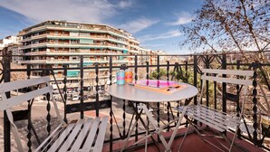 Un balcone con un tavolo tondo e due sedie, con vista su un edificio a più piani con balconi.