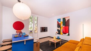 Un soggiorno moderno con zona pranzo blu, un divano giallo e un grande quadro astratto.