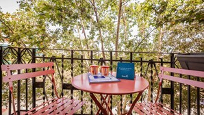 A red metal table and chairs on a balcony with a view of trees. - Sweett | Aragon Park Miro 204 (Barcelona)