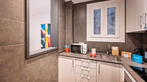 A modern kitchen with a microwave, toaster, sink, and a window above the cabinets. - Sweett | Aragon Park Miro 204 (Barcelona)