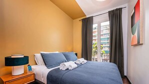 Une chambre d’hôtel avec un lit, une table de chevet, une lampe et une fenêtre avec des rideaux.