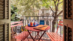 Un balcón con una mesa y sillas rojas, una botella de refresco, una lata de refresco y un menú.
