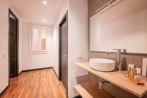 Une salle de bain moderne avec un grand miroir, un lavabo blanc et un revêtement de sol en bois.