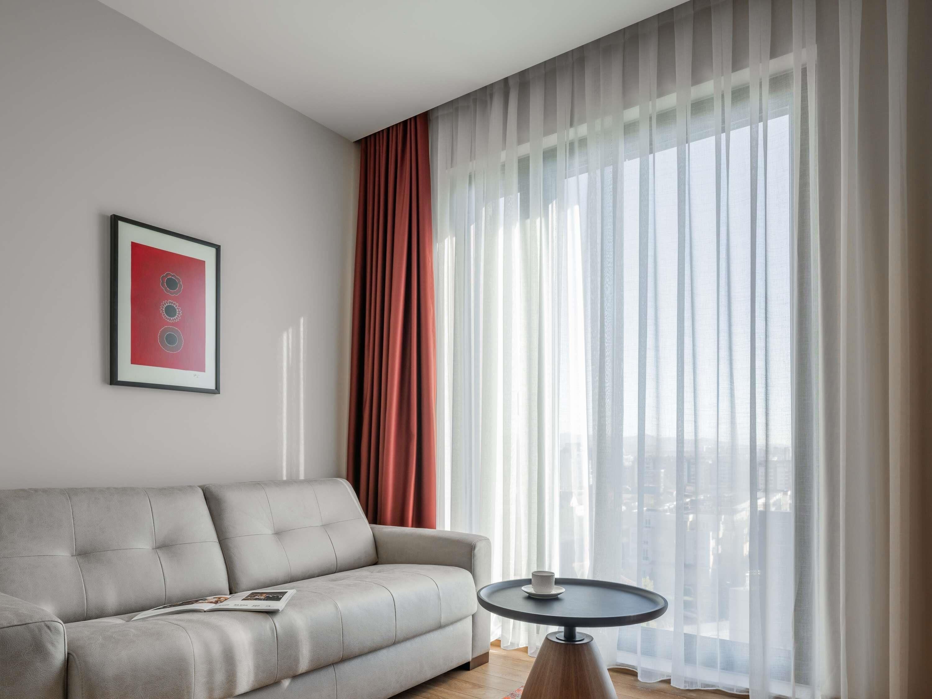 Ein modernes Wohnzimmer mit einem grauen Sofa, einem runden Couchtisch und einem gerahmten Bild an der Wand.