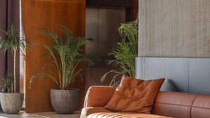 Ein modernes Interieur mit einer Ledersofa, großen Topfpflanzen und einer Kombination aus Holz- und Betonwänden.