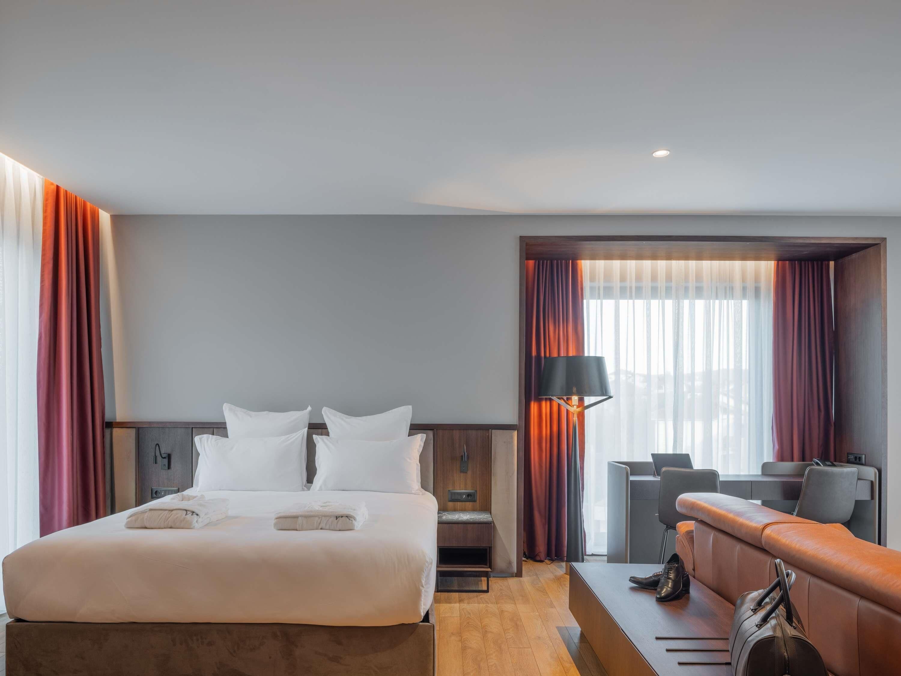 A hotel room with a bed, a desk, and a sofa.