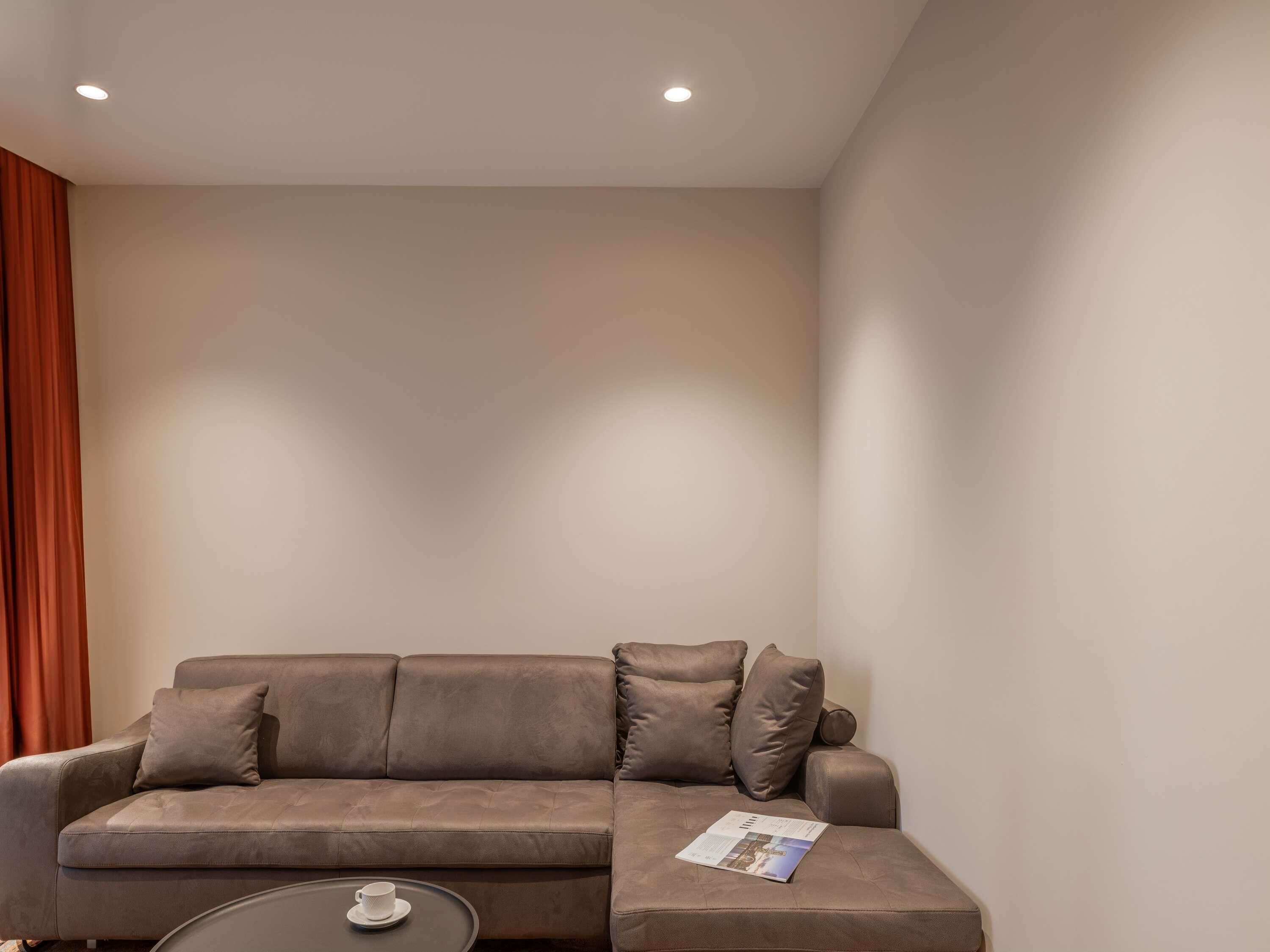 A modern living room with a brown leather sofa, a small round coffee table, and a magazine.