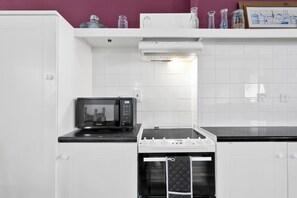 Eine kleine Küche mit Mikrowelle, Backofen und einer Arbeitsfläche.