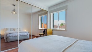 Una camera da letto con un letto grande, una sedia, una scrivania e una finestra vista edifici.