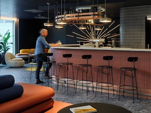 A modern bar area with a counter, multiple stools, and a bar stocked with bottles.