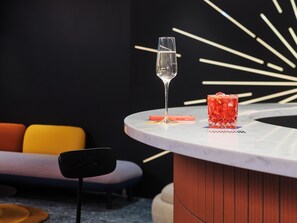 A bar area with a glass of water, a cocktail glass, and a smartphone on a marble surface. - Tribe Baden Baden (Baden-Baden)