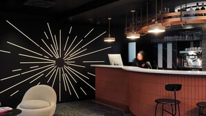 Un espace bar moderne doté d’un comptoir incurvé, de tabourets de bar, d’un coin salon circulaire et d’un éclairage mural au design original.