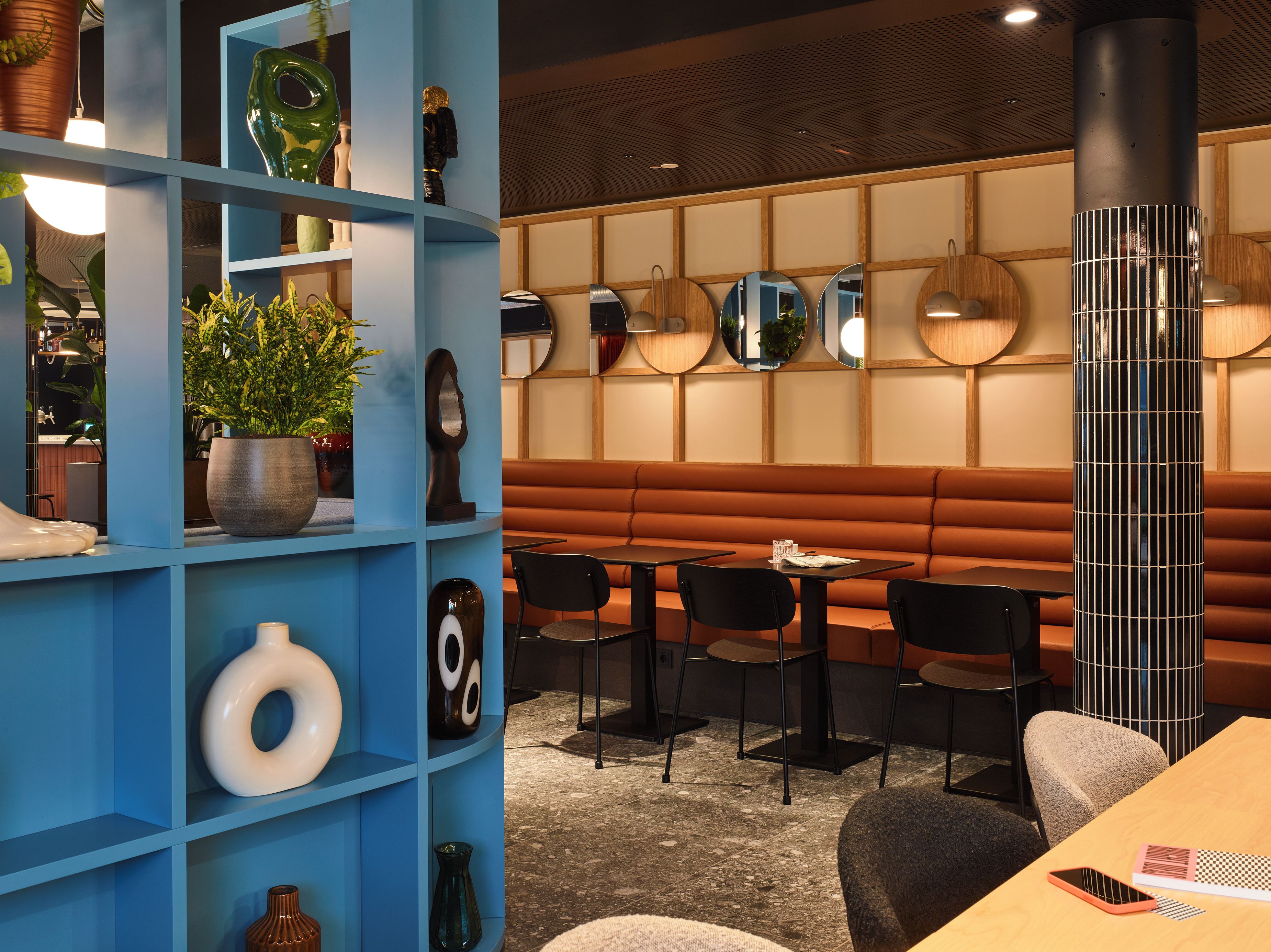 A modern interior with blue shelving, a seating area, and a decorative column.