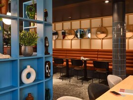 Um interior moderno com prateleiras azuis, um espaço de estar e espelhos decorativos.