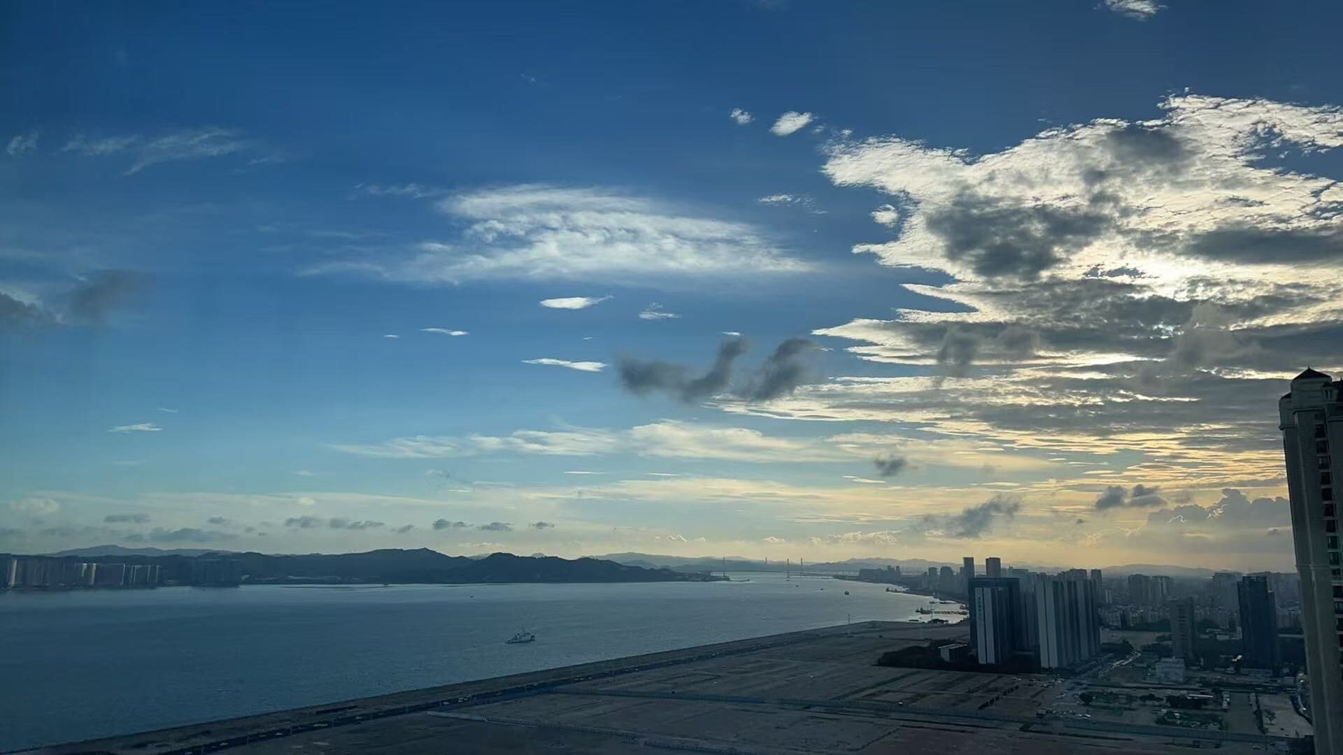 Un paisaje costero con vista al mar, un puente y rascacielos.