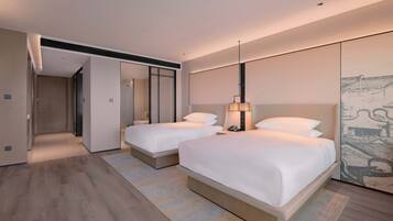 A modern hotel room with two beds, a large mirror, and a wall-mounted artwork.
