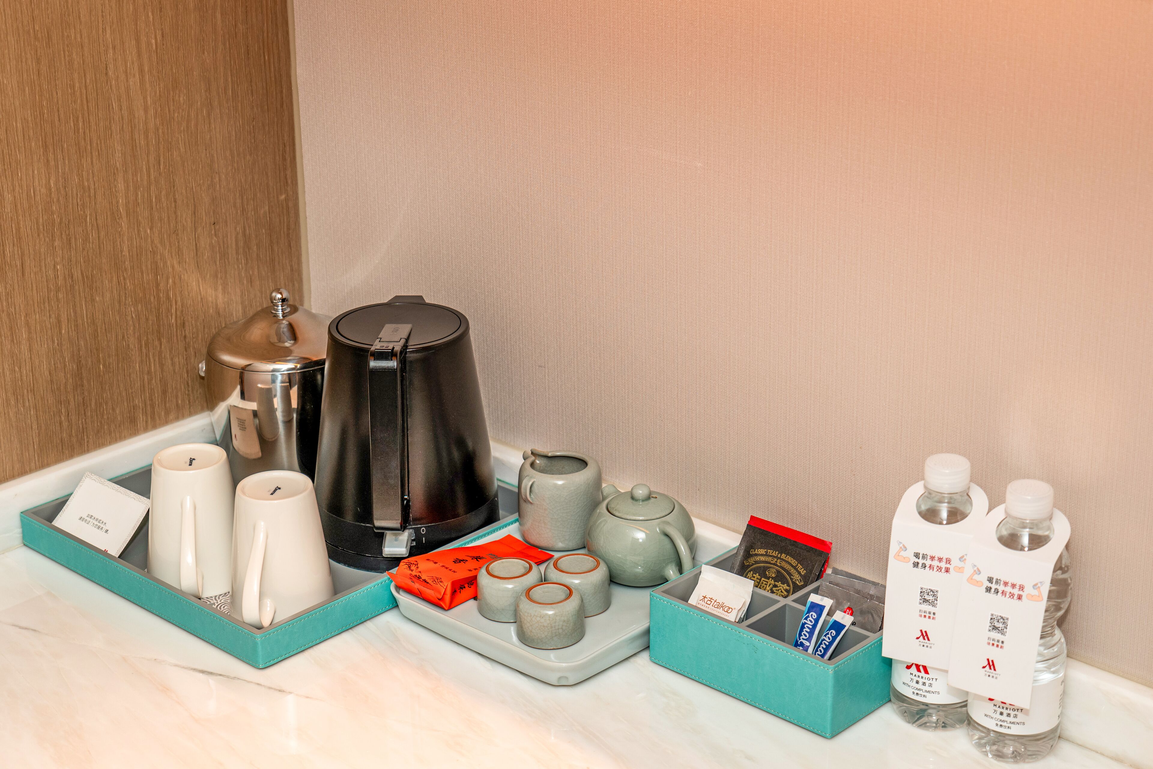 A tray with tea set, a coffee maker, and bottled water.