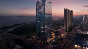 Un hotel de gran altura con el logotipo de Marriott, rodeado de otros edificios y una masa de agua.