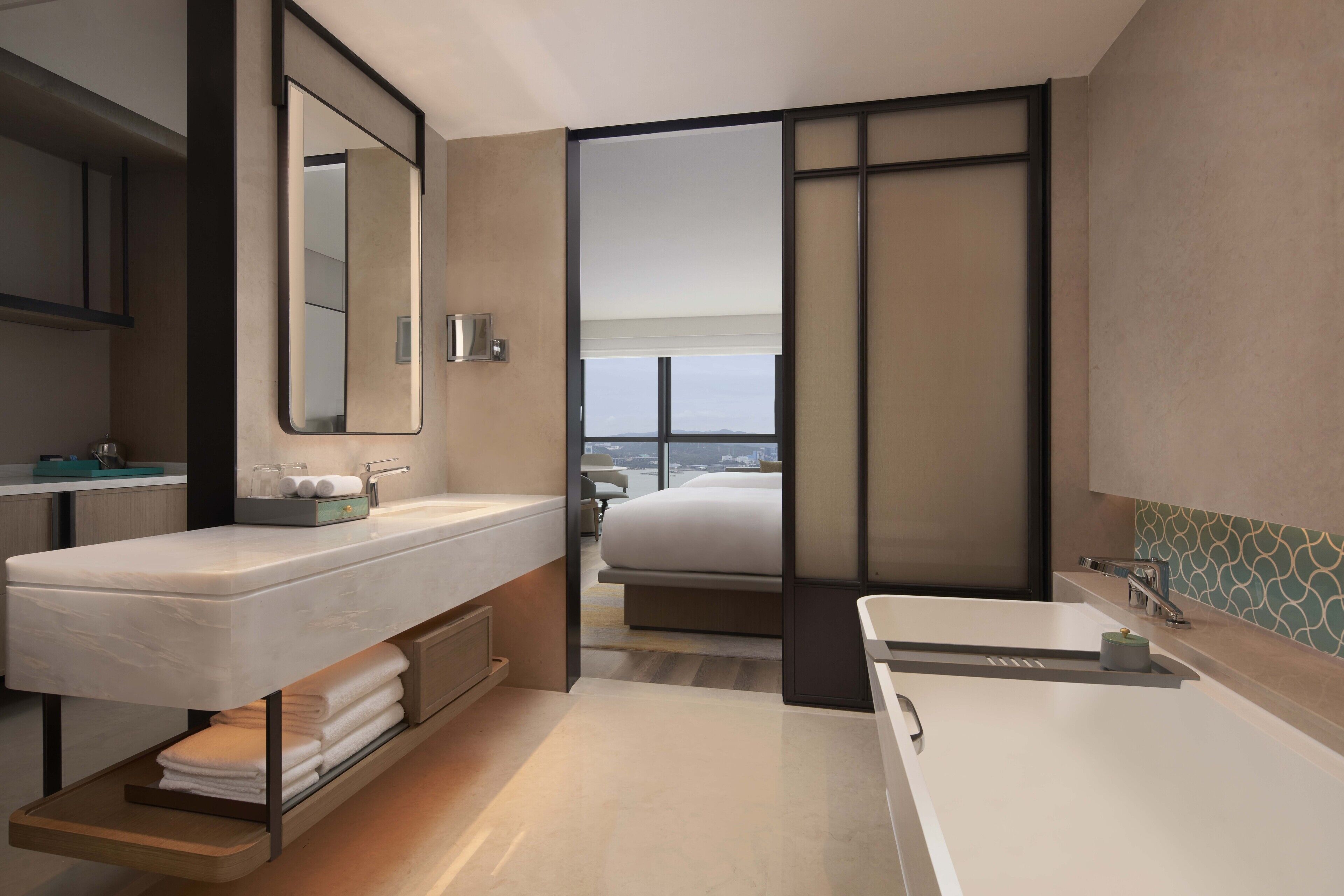 Un baño de hotel moderno con un espejo grande, una bañera y un tocador con encimera.