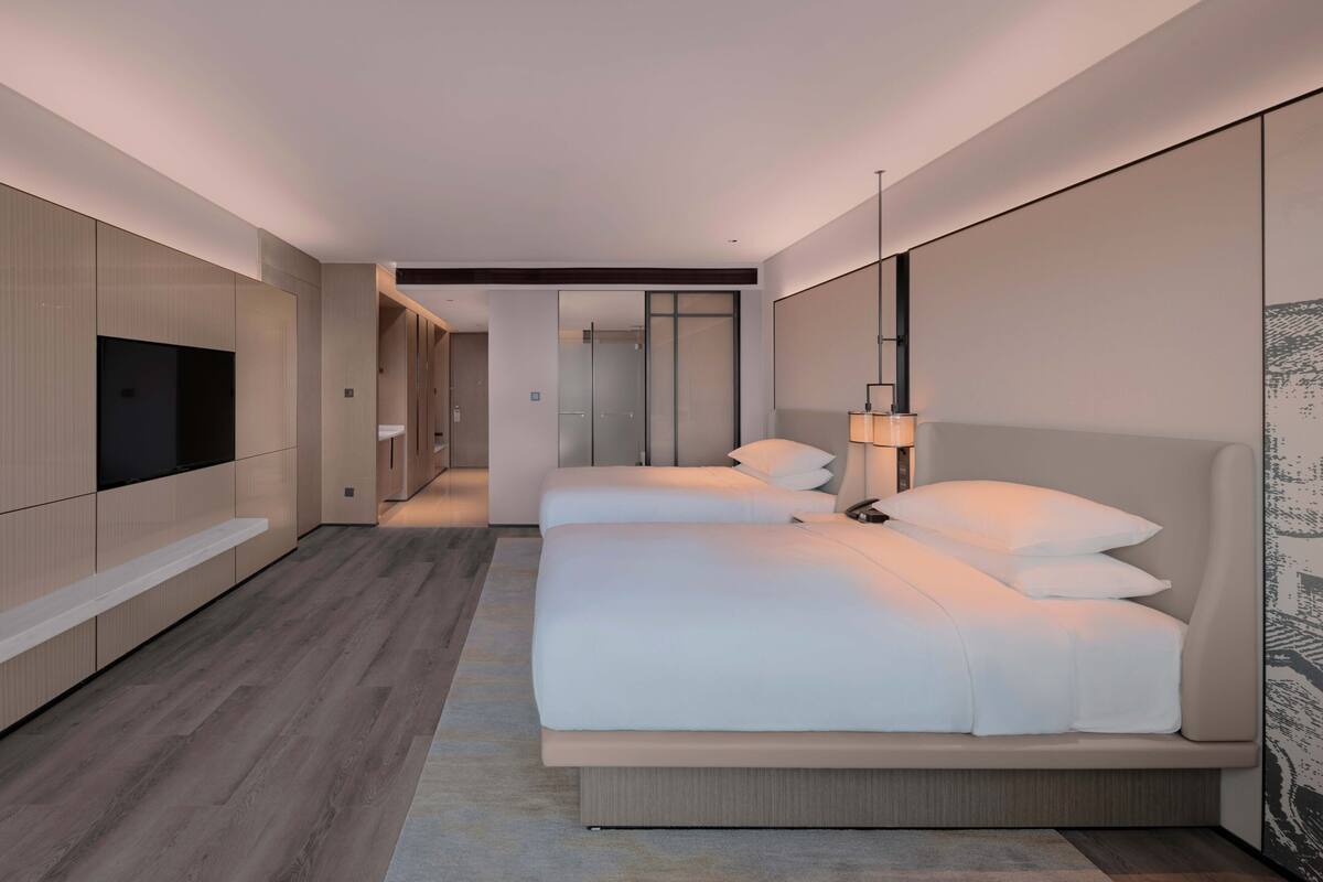 A modern hotel room with a large bed, a TV, and a walk-in closet.