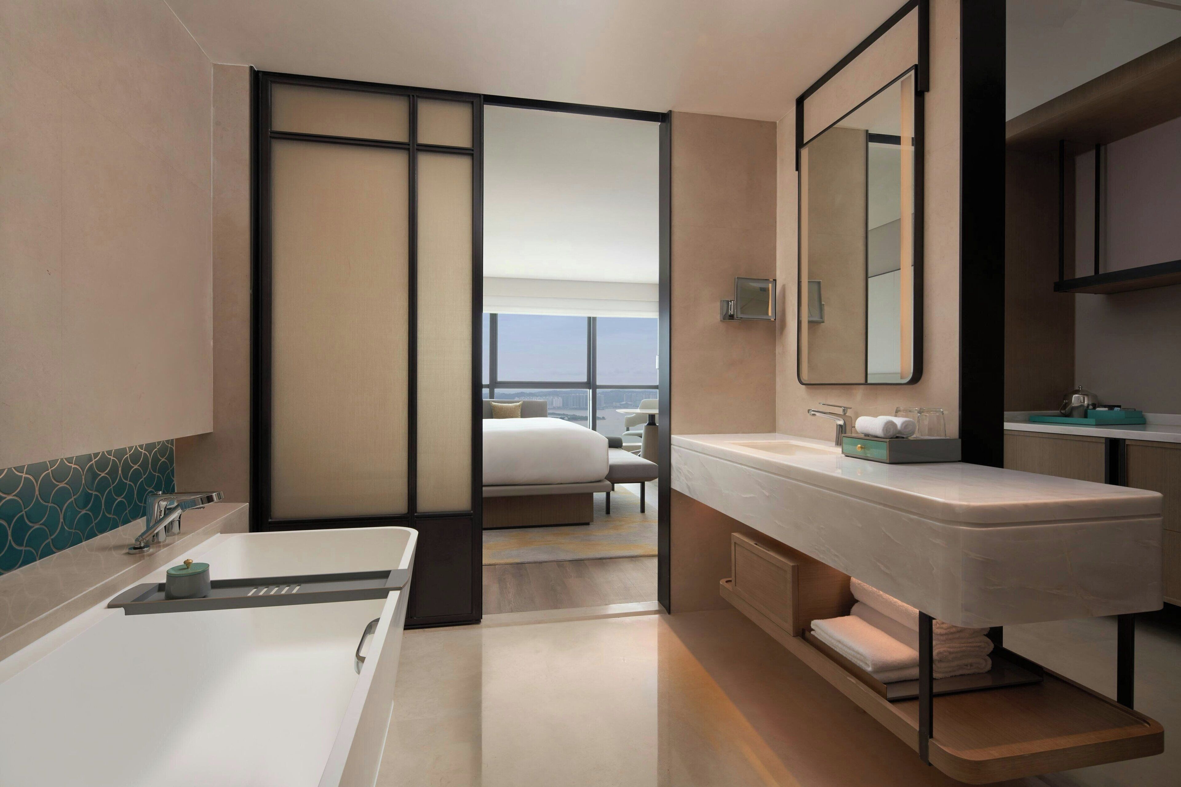 A modern hotel bathroom with a bathtub, a large mirror, and a sink.