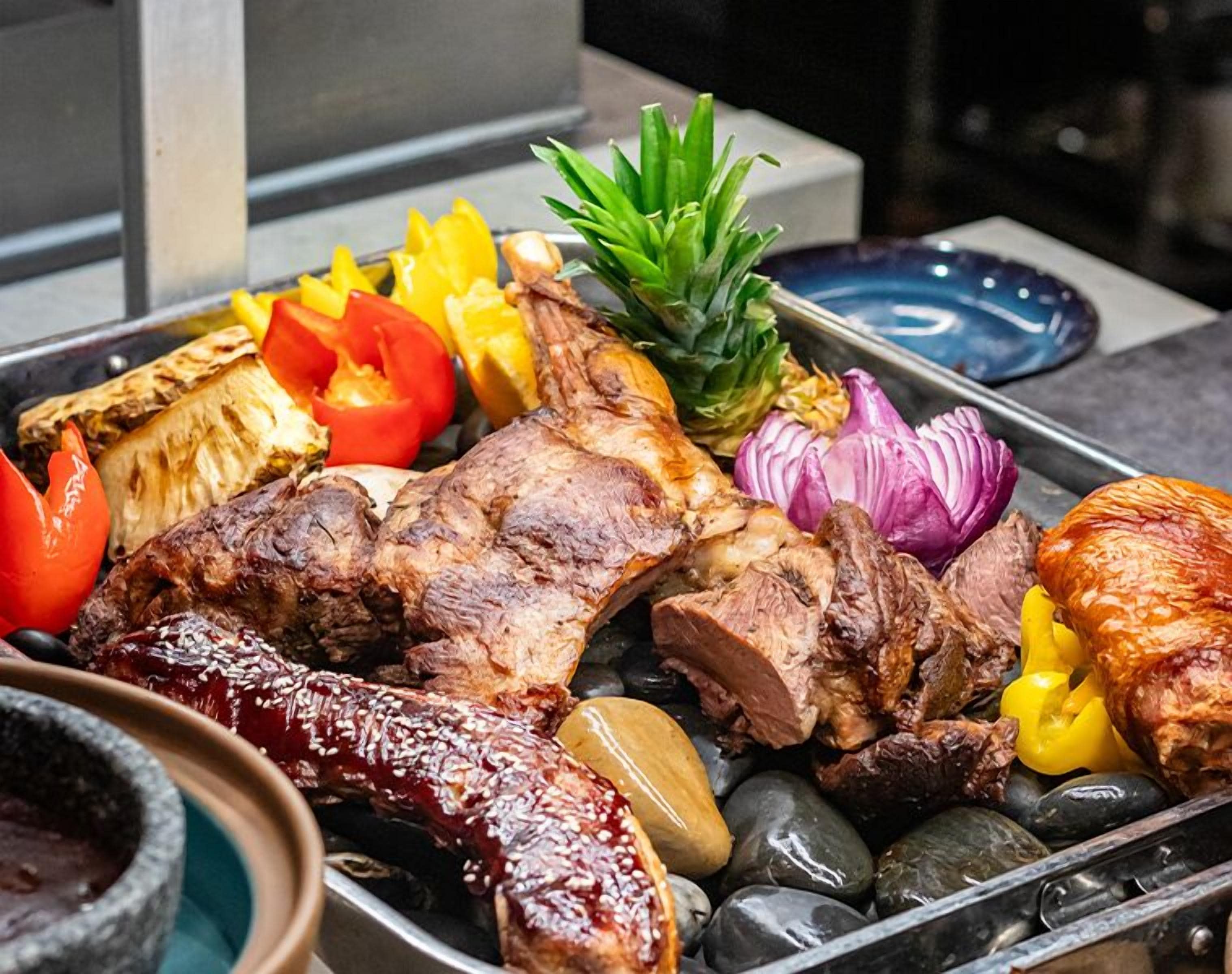 A variety of grilled meats and vegetables on a tray.