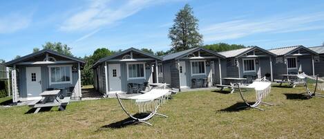 A row of small, single-story cabins with attached patios, numbered from 1B to 5B, under a clear sky.