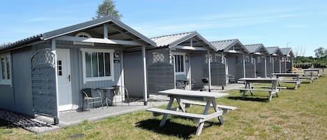 A row of single-story cabins with attached picnic tables, each with a small porch and a window.