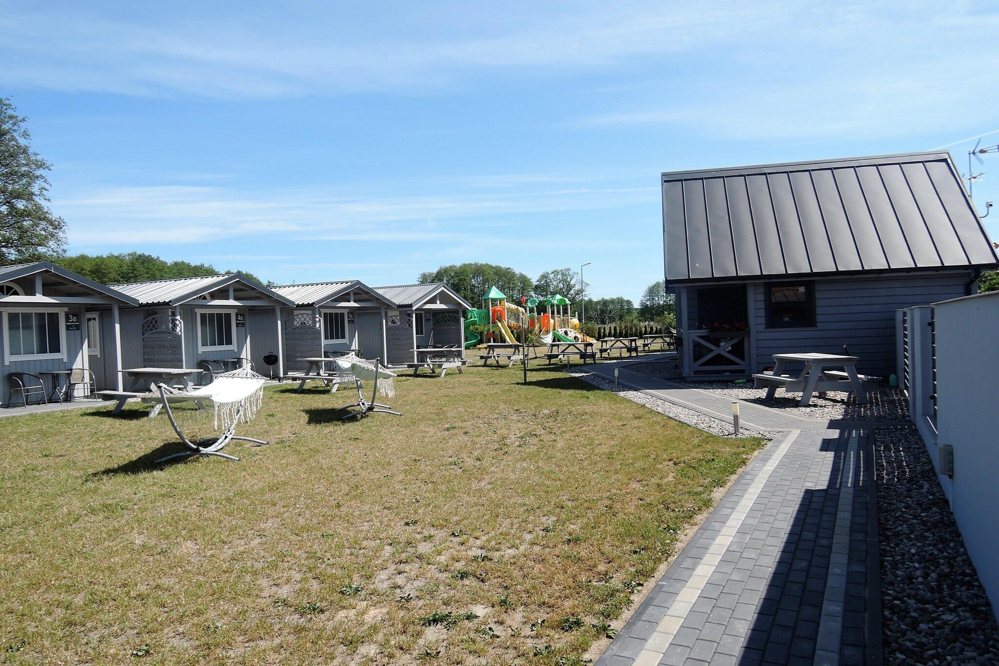 A campground with mobile homes, picnic tables, and a playground.